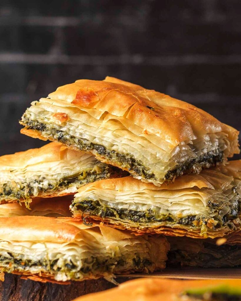 Squares of baked vegan spanakopita stacked on top of each other.