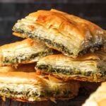 Squares of baked vegan spanakopita stacked on top of each other.