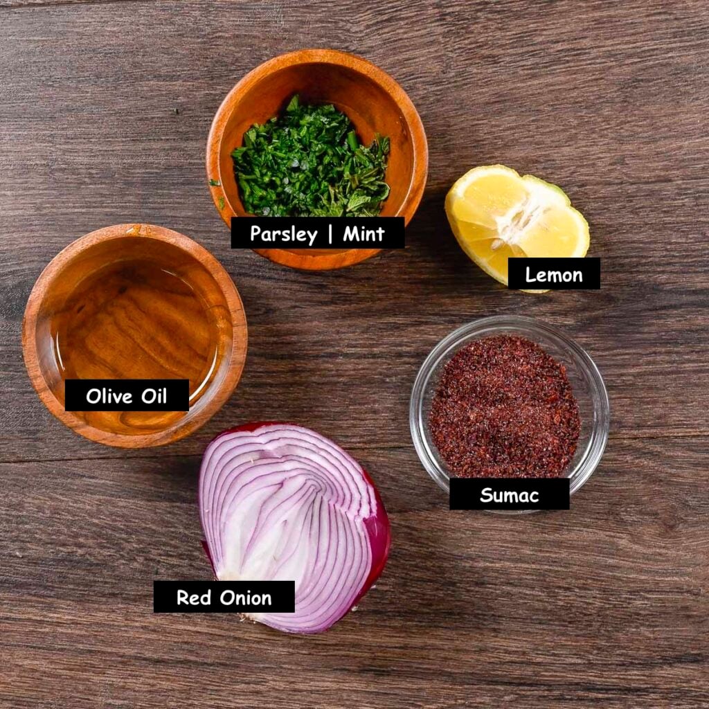 Ingredients used in making marinated red onions (red onion, sumac, lemon, olive oil, flat leaf parsley, and mint).