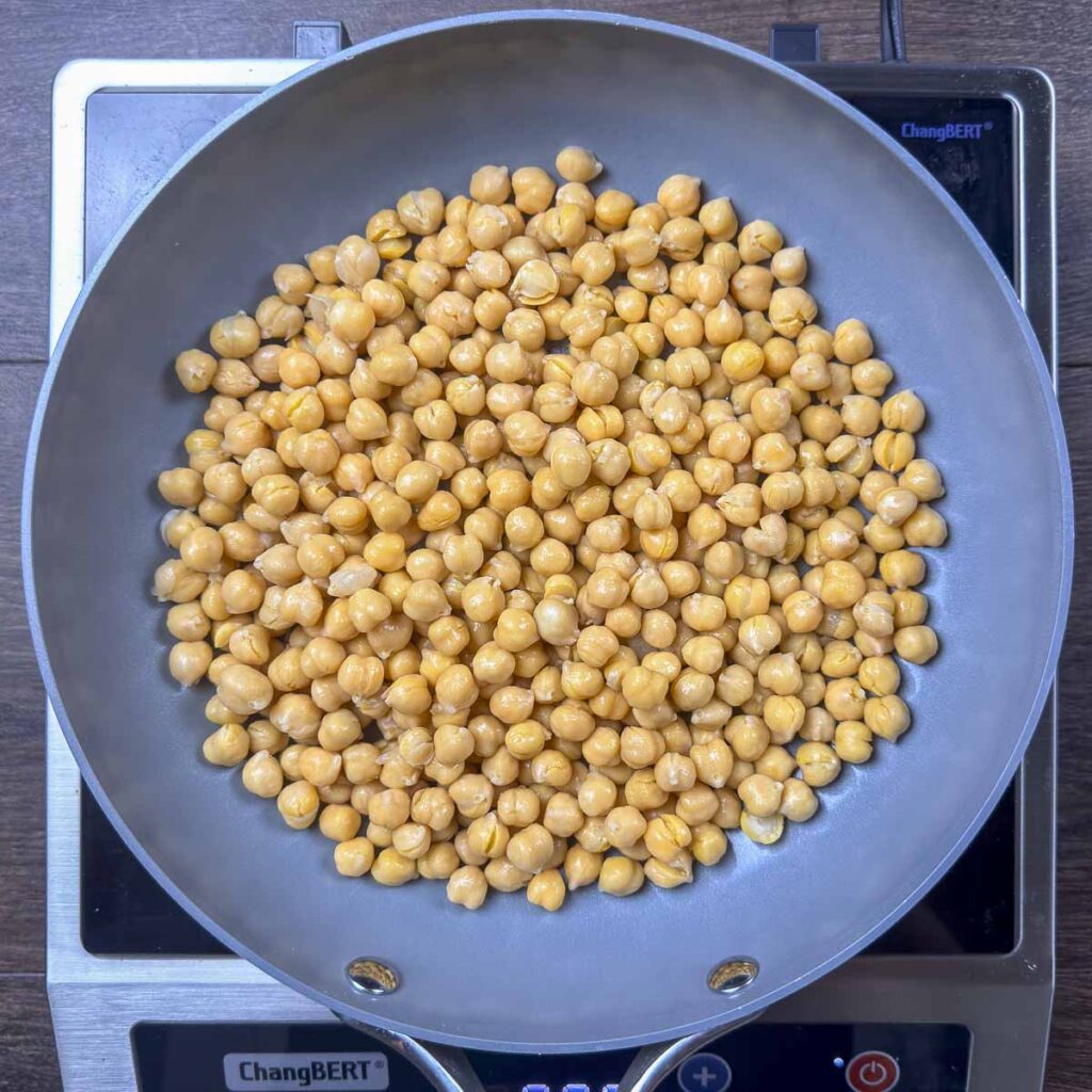Dry toasting two cans of chickpeas in a skillet.