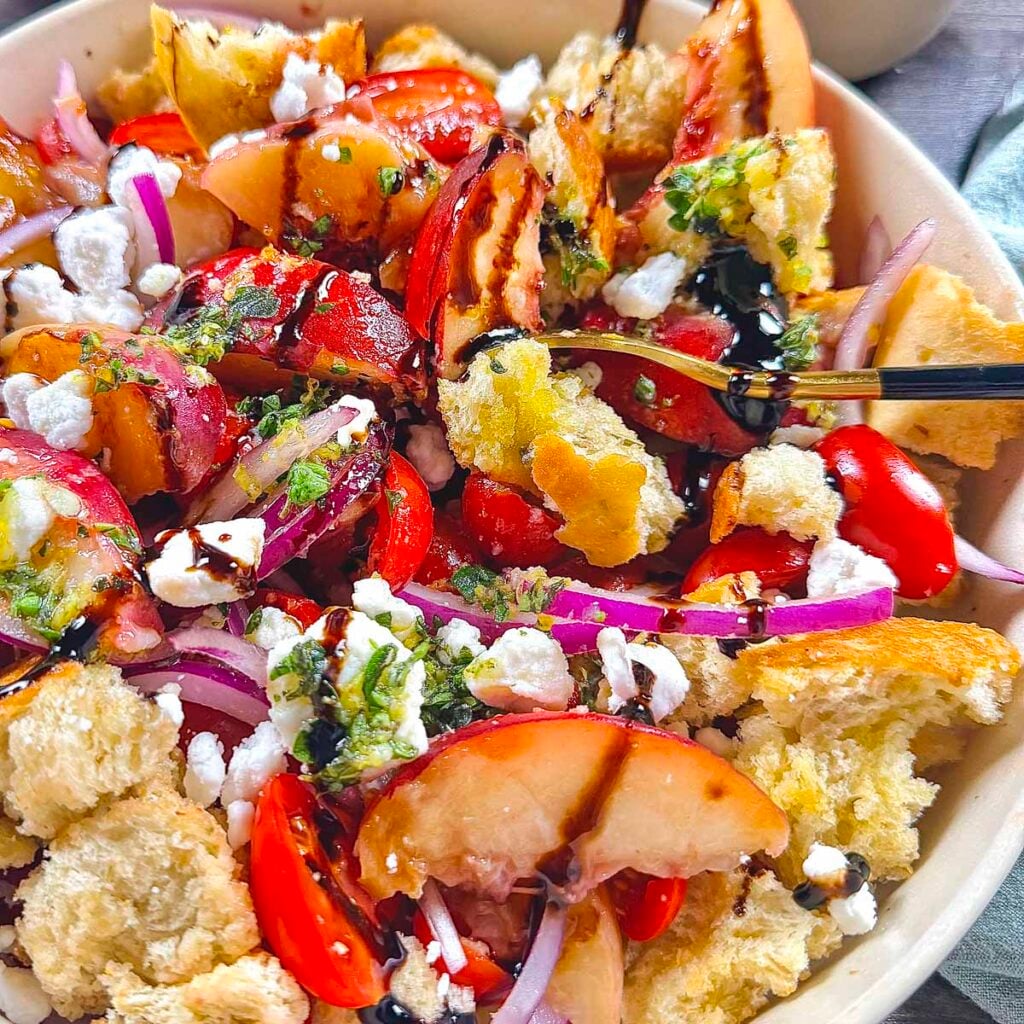 Grilled peach panzanella salad up close with vegan feta cheese and balsamic glaze on top.
