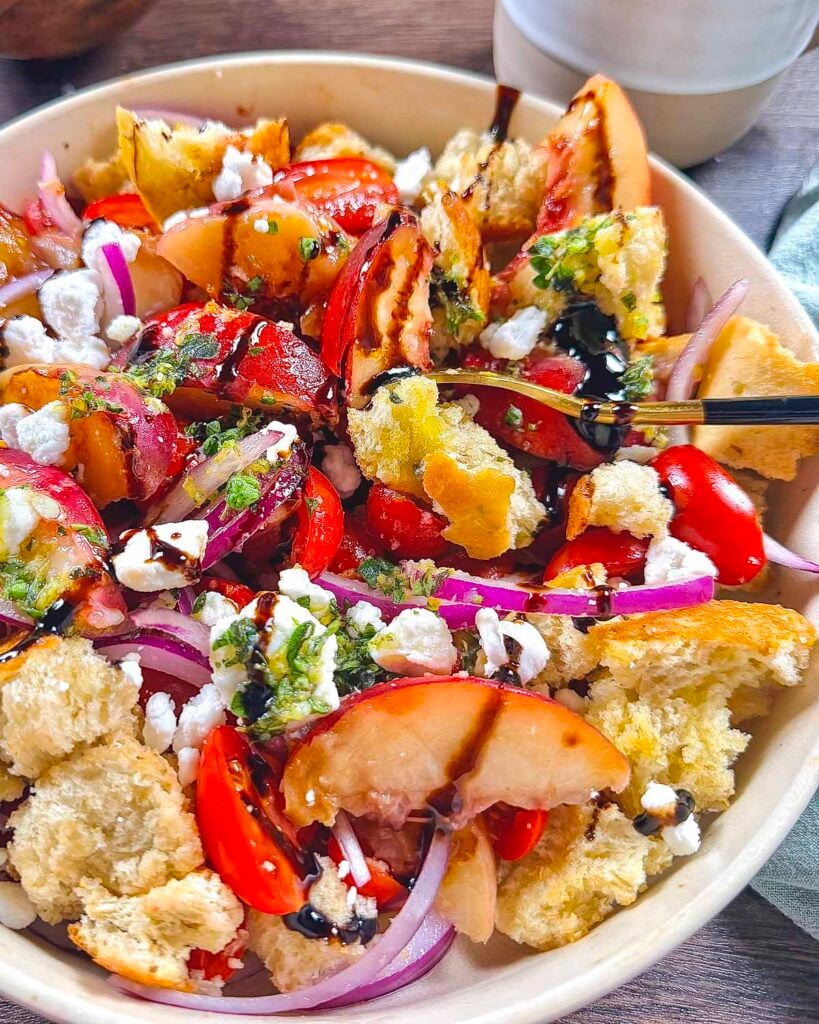 Grilled peach panzanella salad up close with vegan feta cheese and balsamic glaze on top.