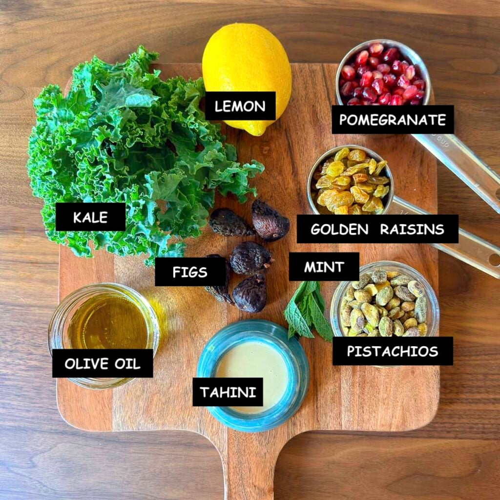 Ingredients for Mediterranean kale salad: curly kale, dried figs, tahini, golden raisins, lemon, fresh mint leaves and pomegranate arils.