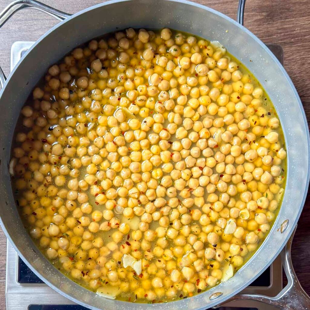 Sautéed chickpeas simmering in vegetable broth.