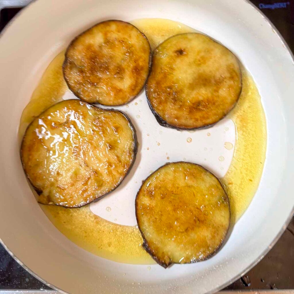 Eggplants fried to a golden brown in a skillet.