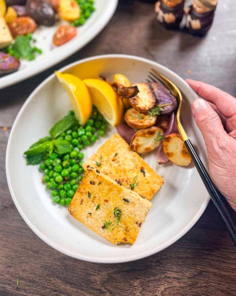 A plate filled with lemon oregano tofu, roasted new potatoes, and mint peas.