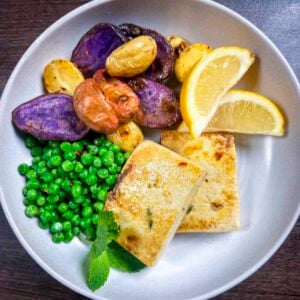 A plate filled with lemon oregano tofu, roasted new potatoes, and mint peas.