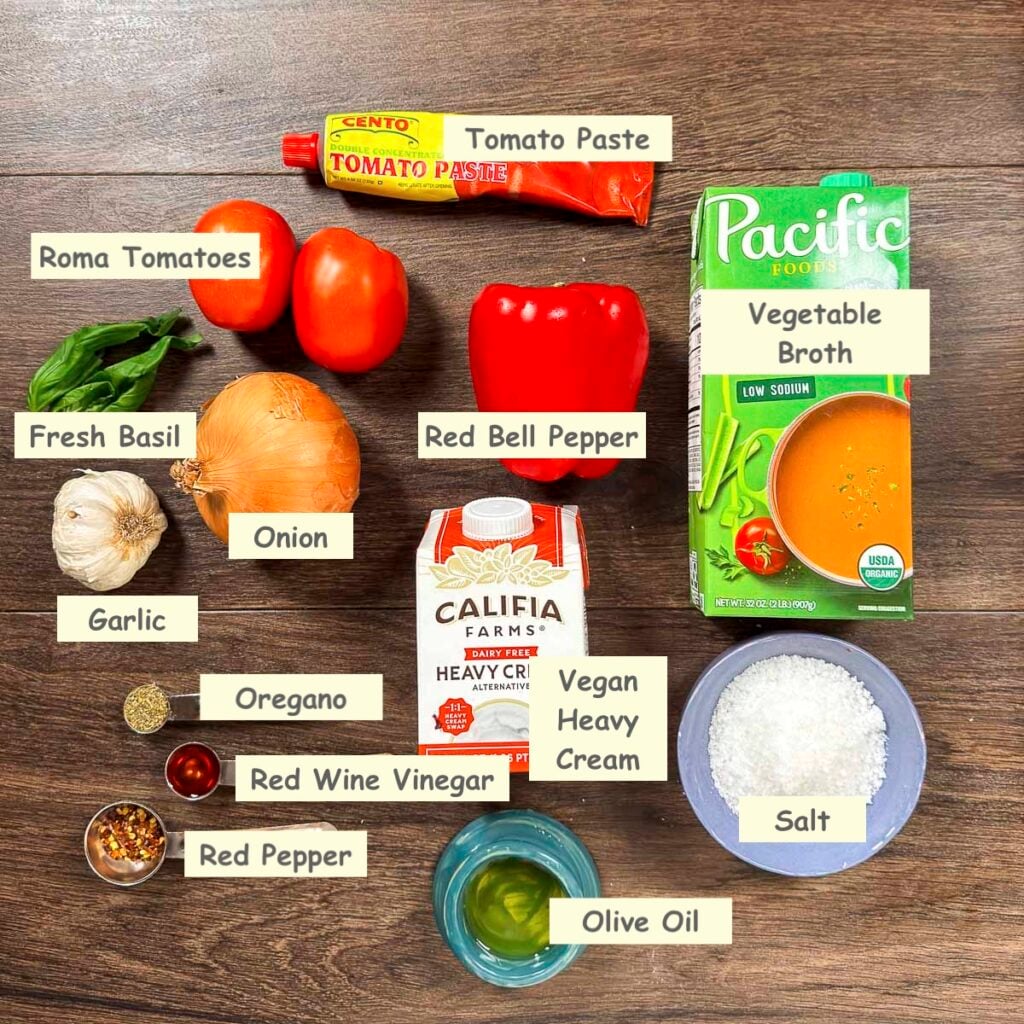 Ingredients used in making vegan tomato and red pepper soup (red bell peppers, Roma tomatoes, tomato paste, vegetable broth, fresh basil leaves, onion, garlic, vegan heavy cream, olive oil, oregano, red wine vinegar, and crushed red pepper flakes.