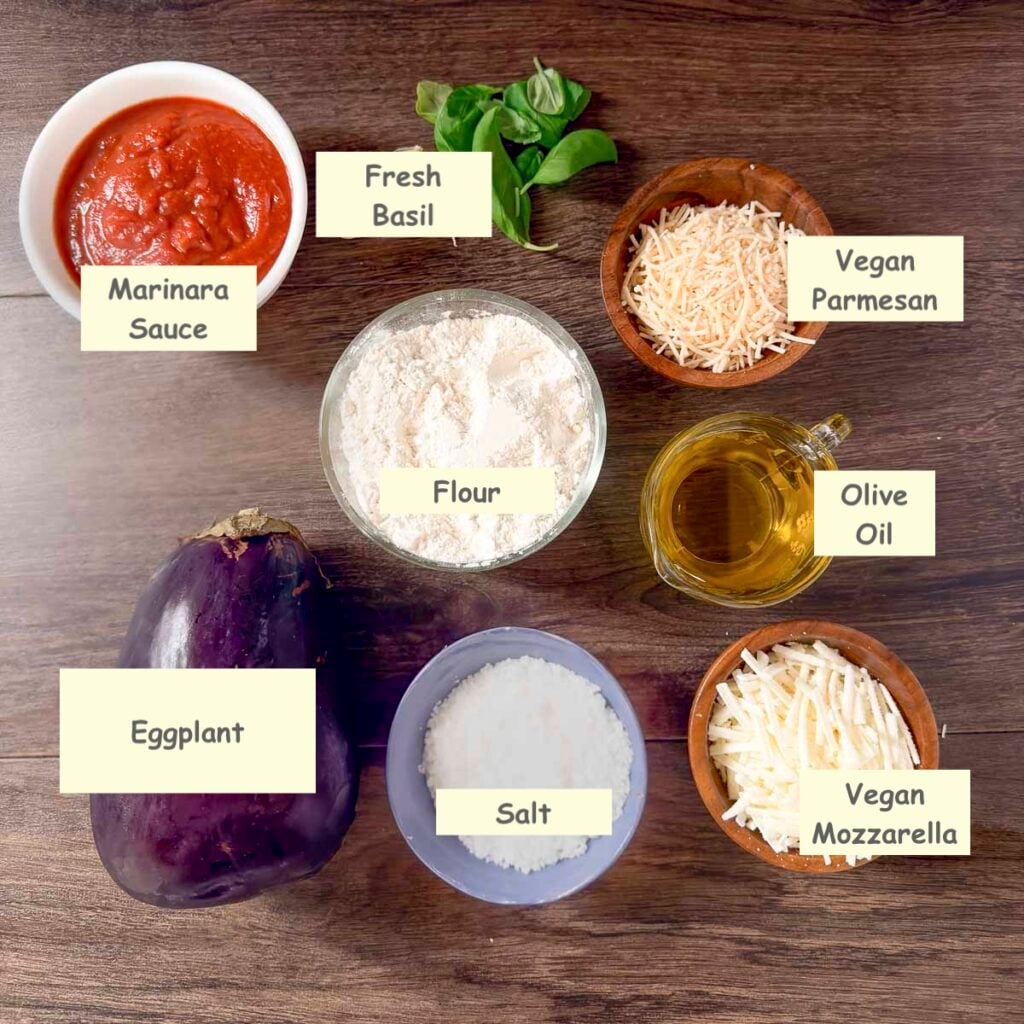 Ingredients used in making skillet eggplant parmigiana: eggplant, marinara sauce, flour, salt, fresh basil, olive oil, vegan Parmesan, and vegan mozzarella.