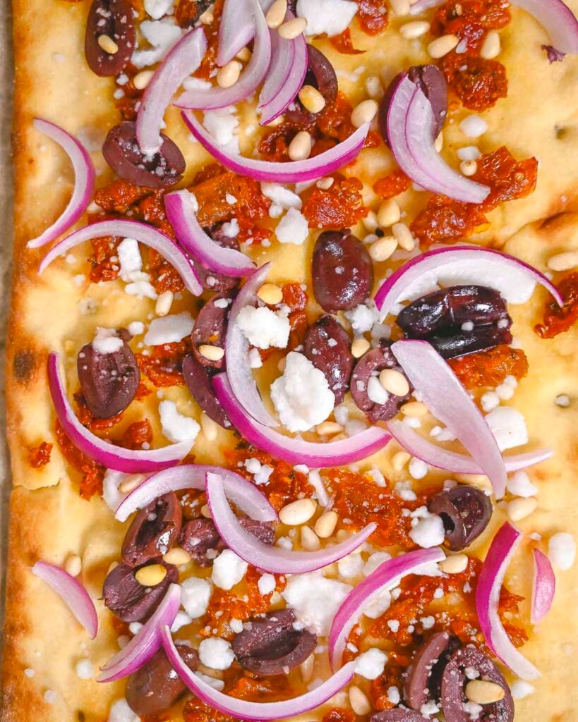 Vegan flatbread pizza with the ingredients on top before it is baked.