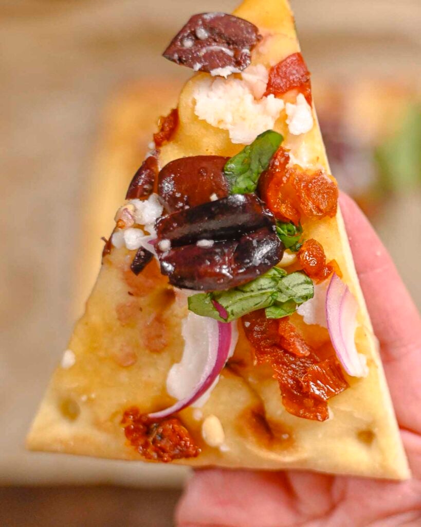 A slice of Mediterranean flatbread pizza up close.
